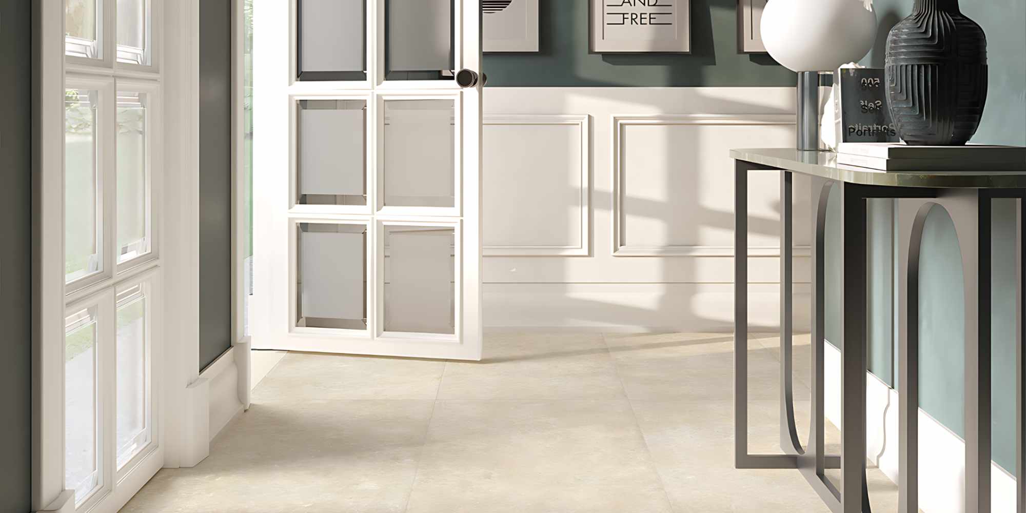 L'immagine mostra un elegante ingresso contemporaneo valorizzato dalla collezione CATHEDRALE nel colore Paris Creme, una superficie ispirata alla pietra calcarea naturale caratterizzata da tonalità beige calde e da una texture morbida e autentica. La posa nel formato 60x120 cm crea un effetto visivo uniforme e raffinato, capace di ampliare lo spazio e di esaltare la luminosità proveniente dalle ampie vetrate laterali.
Le sfumature delicate e le leggere variazioni cromatiche del Paris Creme dialogano armoniosamente con le boiserie bianche, le pareti verde salvia e gli elementi d'arredo dal gusto contemporaneo, creando un ambiente accogliente e sofisticato. La luce naturale mette in risalto la matericità della superficie, conferendo profondità e un realismo che richiama il fascino senza tempo della pietra naturale.